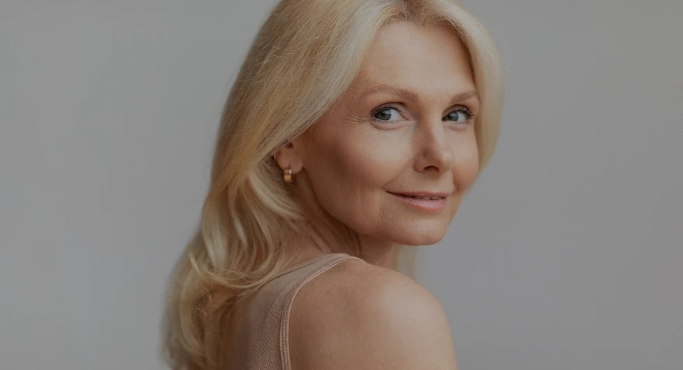 older woman looking over her shoulder Dr Olatomide (Tomi) Famalusi | Élevé Plastic Surgery Plastic Surgery Atlanta