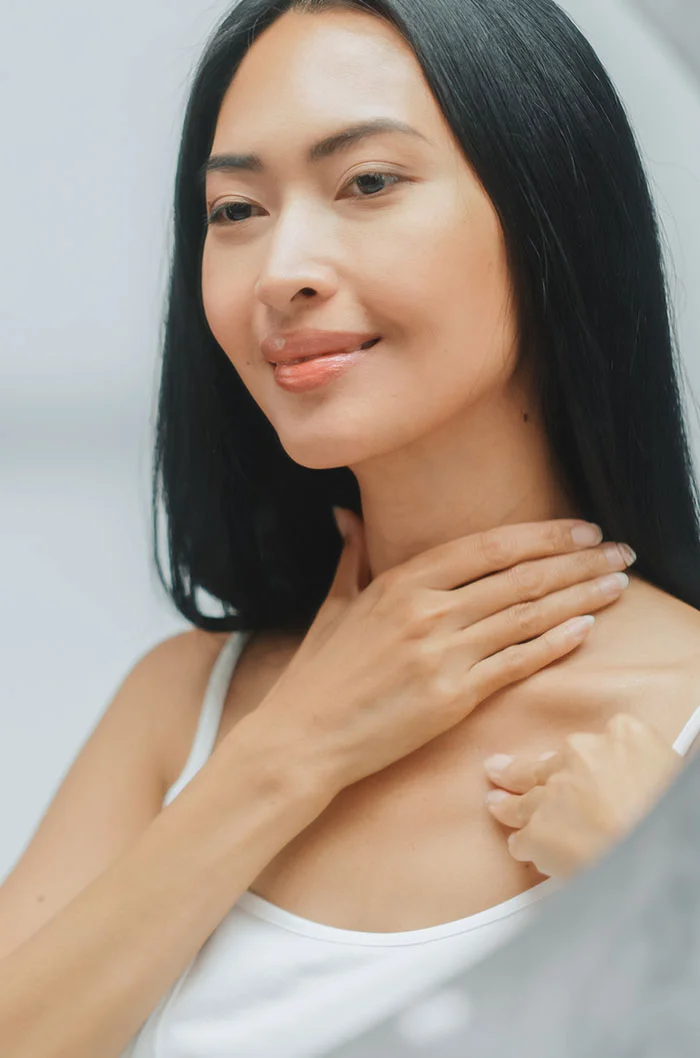 A woman with dark hair, touching her neck - Skin Cancer Reconstruction in Marietta, GA